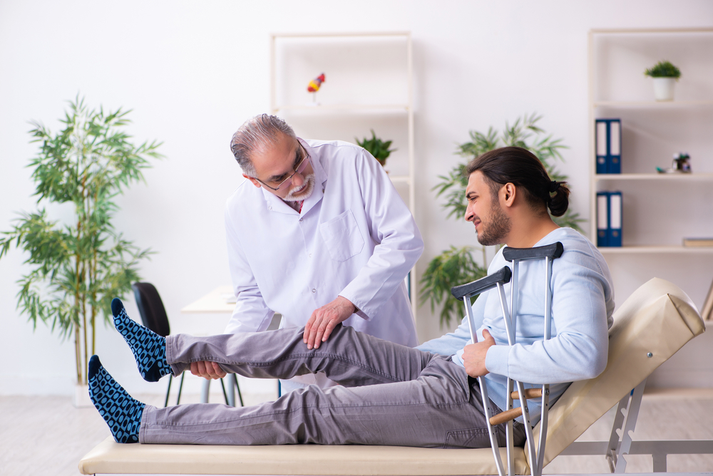 Young leg injured man visiting old doctor osteopath